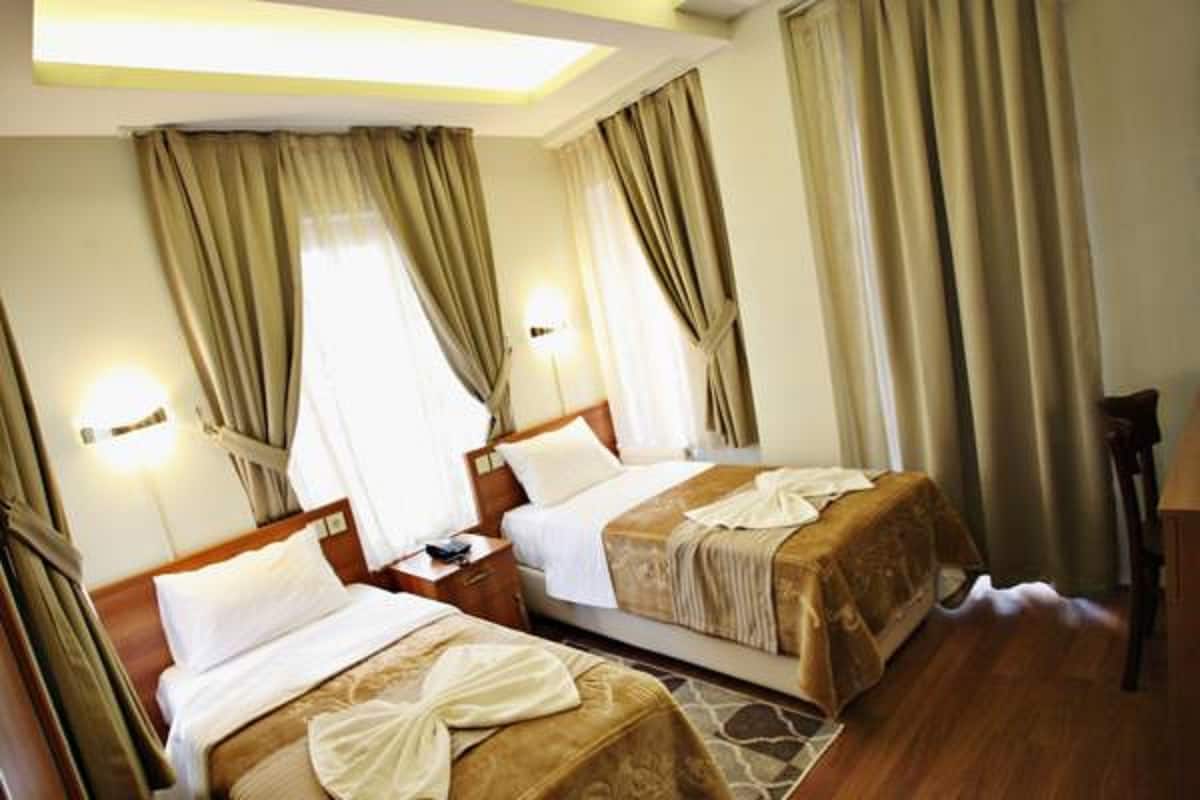 A hotel room with two beds, wooden headboards, and a nightstand with a lamp.
