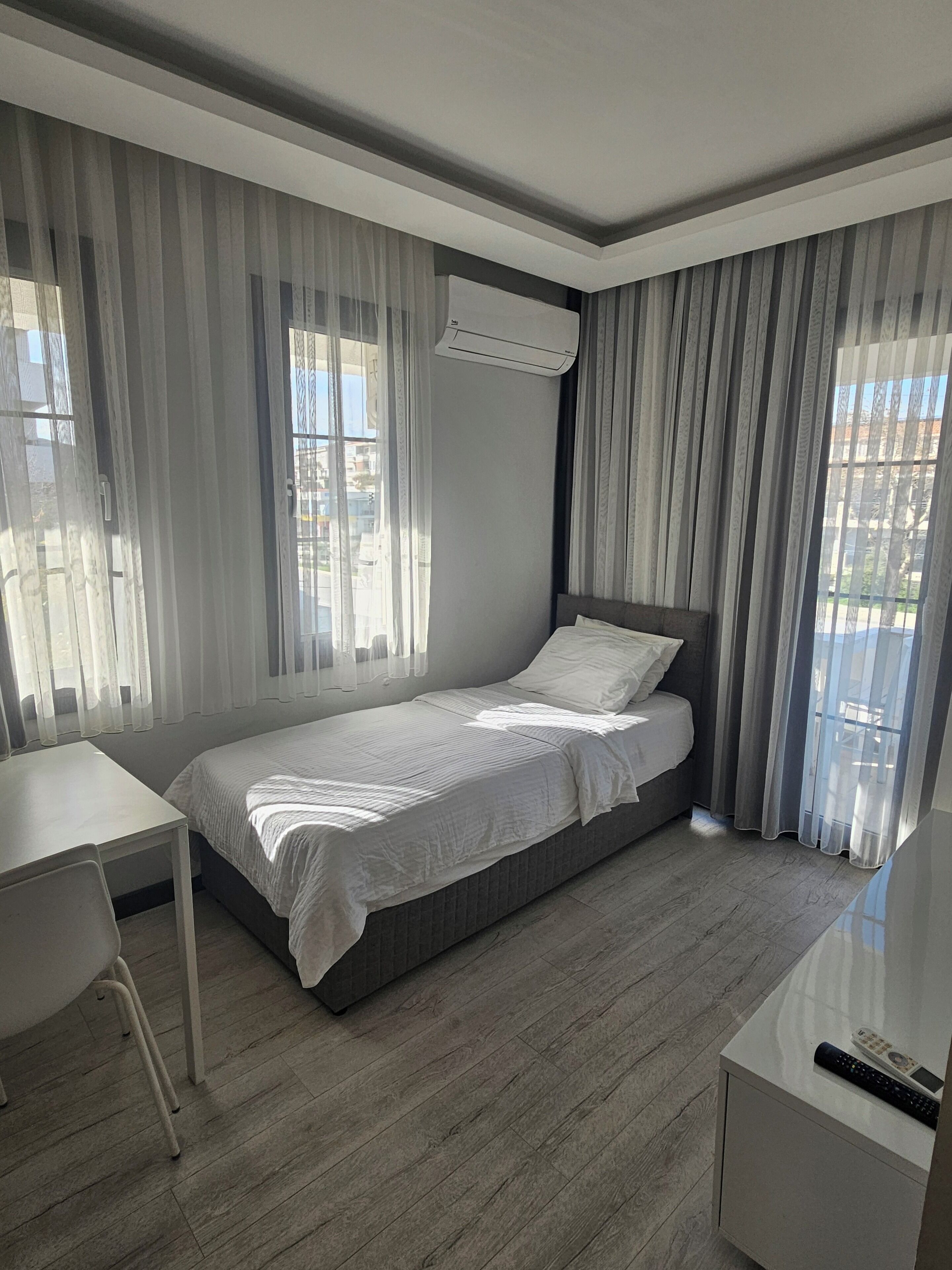 Ein modernes Schlafzimmer mit einem Einzelbett, einem Schreibtisch und einem Einbauschrank.