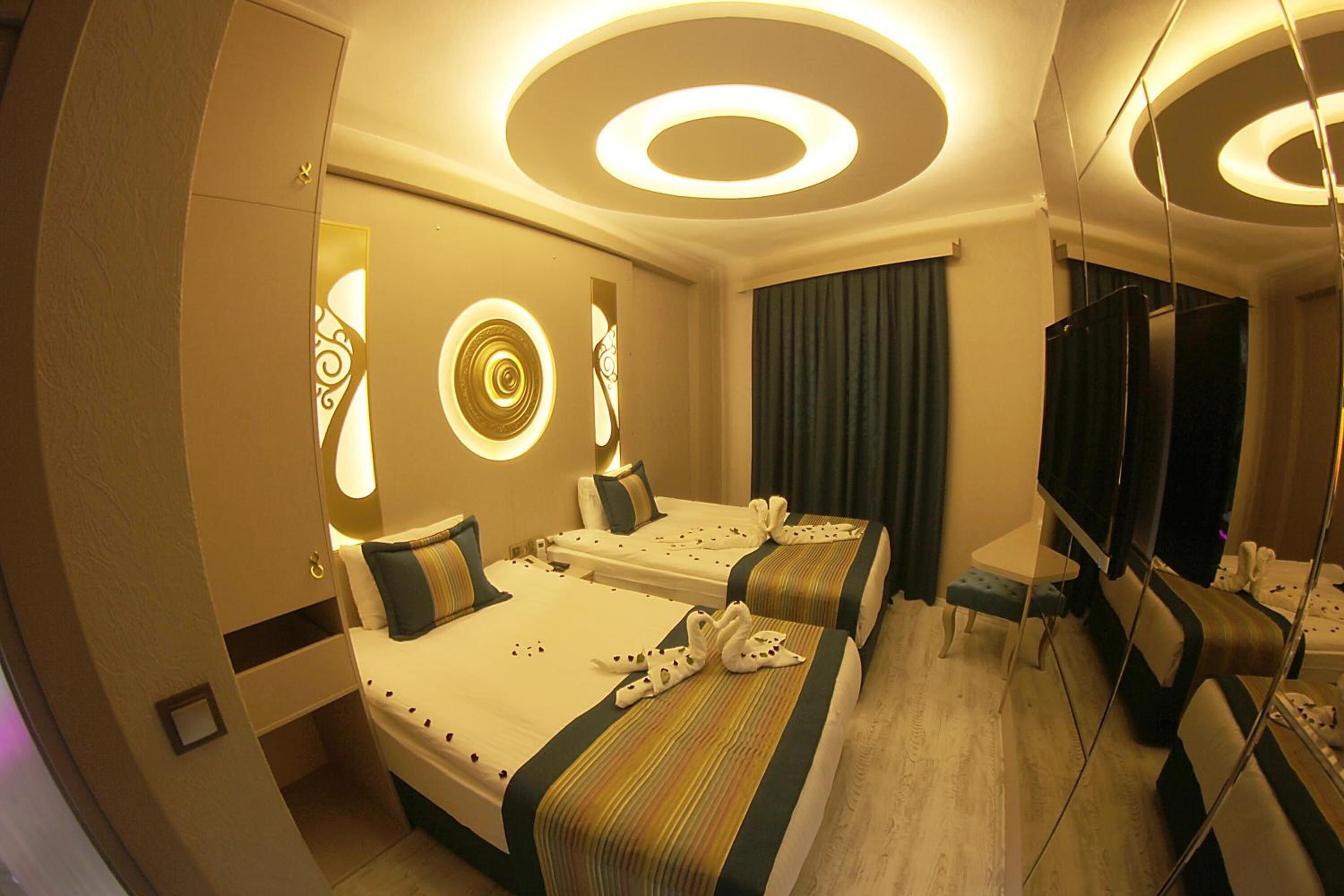 A hotel room with two beds, a TV, a desk, and a mirror.