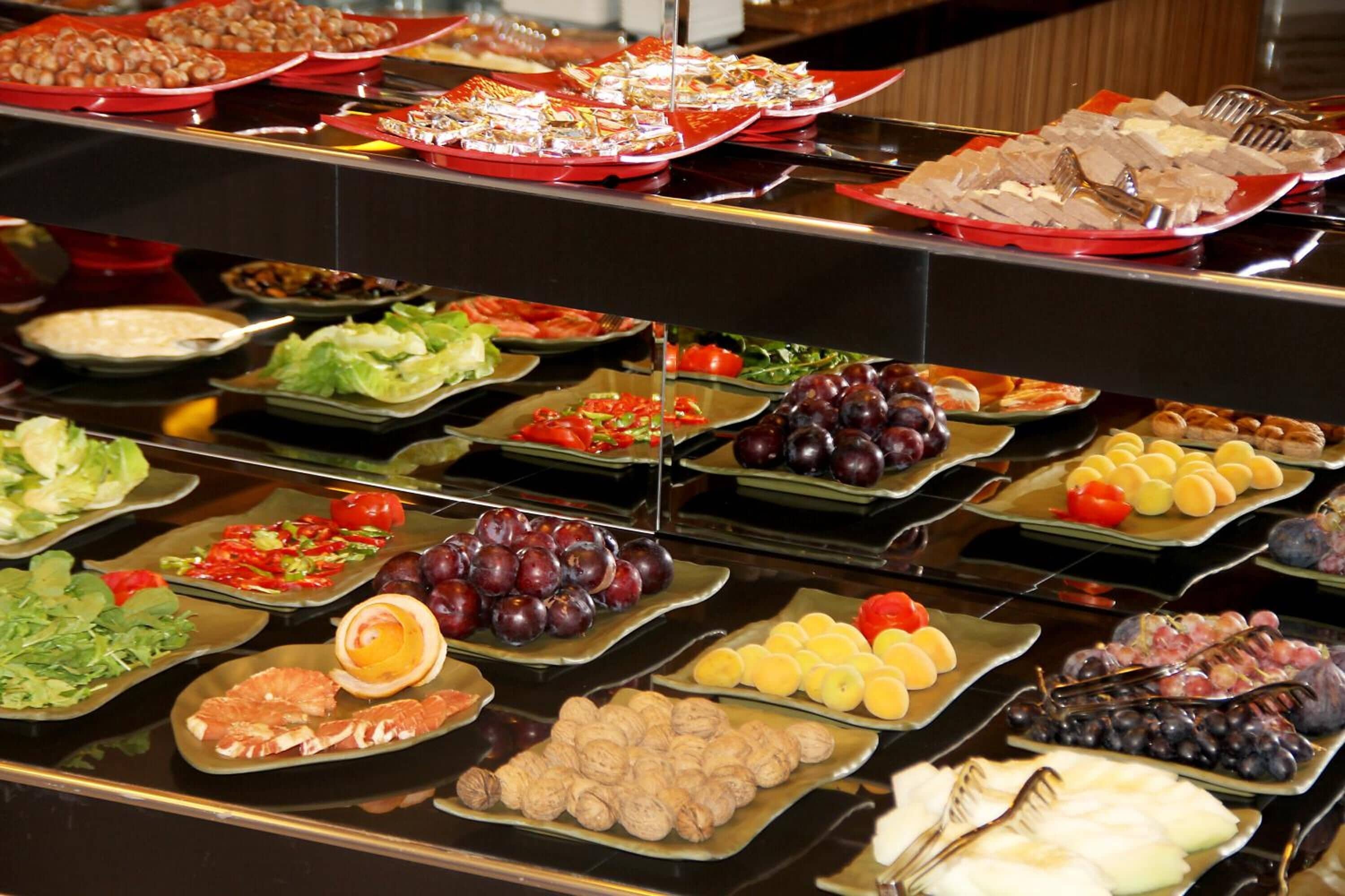 A buffet with various food items including fruits, vegetables, and meats.