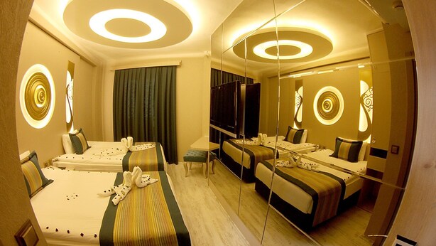 A hotel room with two beds, a desk, and a large mirror reflecting the room. - Nun Otel (Konya)