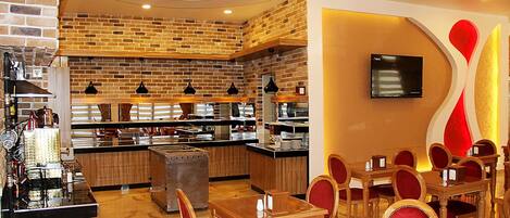 A restaurant with brick walls, wooden tables and chairs, and a TV mounted on the wall.