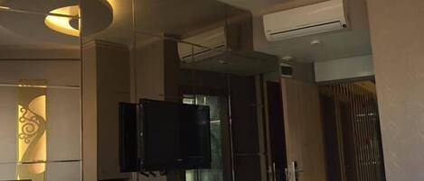 A modern hotel room with a large bed, a desk with a chair, a flat-screen TV, and a mirror.