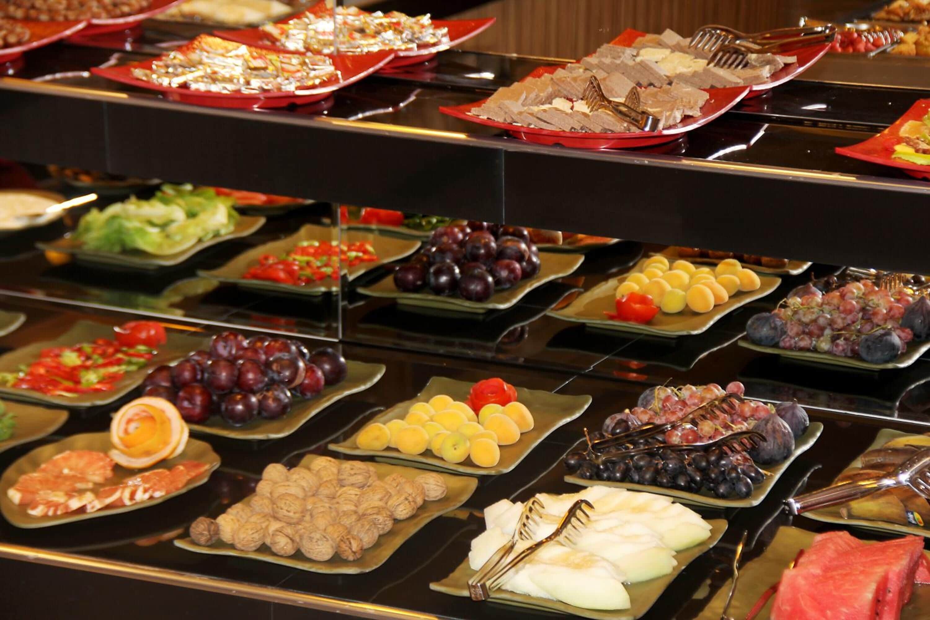 A buffet with various food items including fruits, vegetables, and meats.