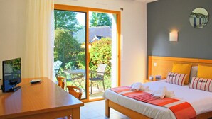 A hotel room with a bed, a desk, a chair, and a view of the outdoors. - Azureva Tregunc (Tregunc)