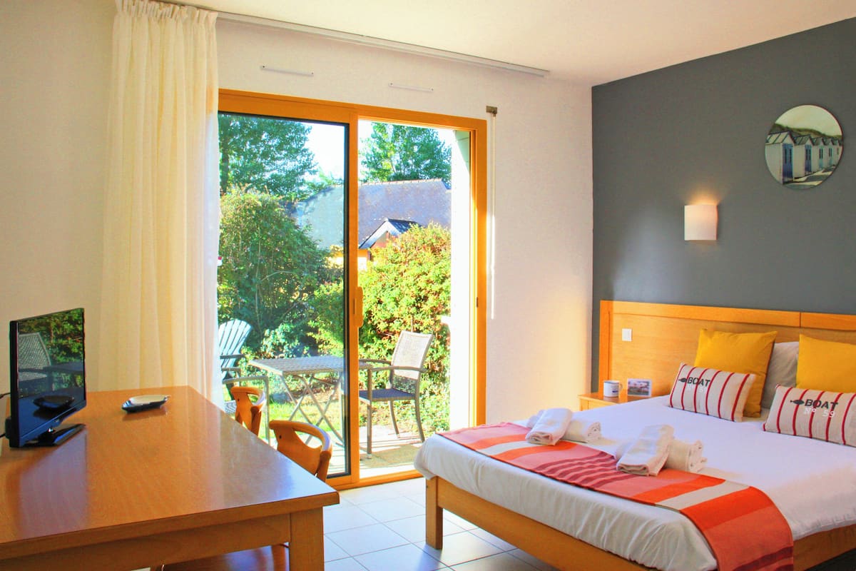A hotel room with a bed, a desk, a chair, and a view of the outdoors.