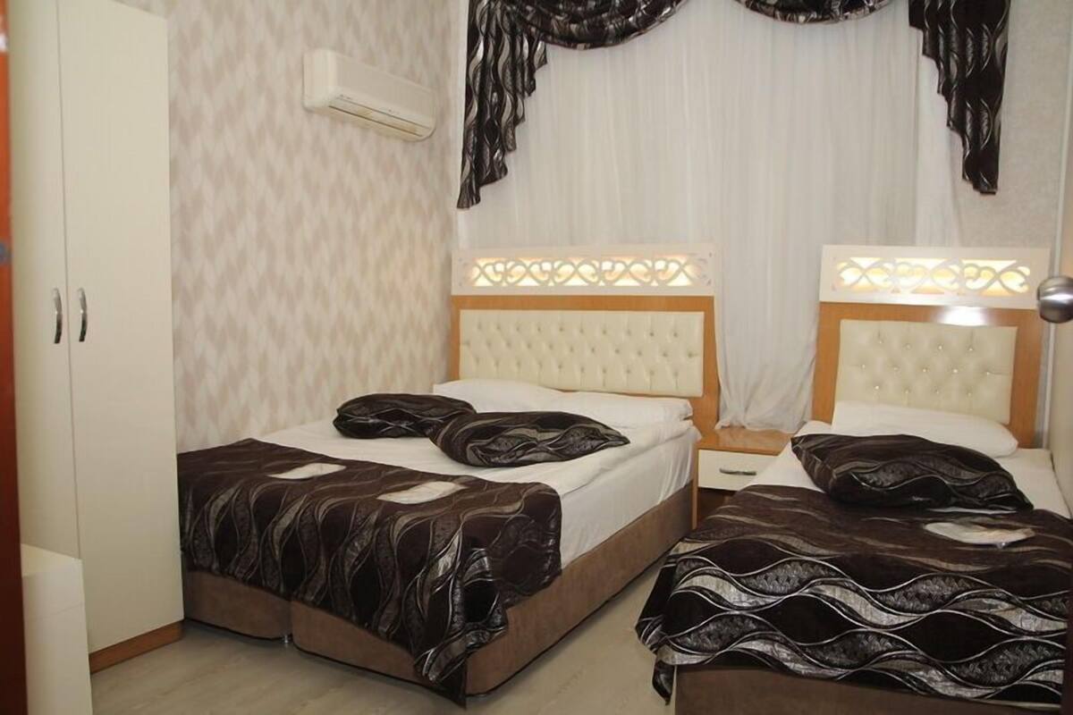 A hotel room with two beds, a wardrobe, and a decorative headboard.