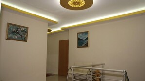 A hallway with a ceiling light fixture, two framed pictures on the walls, and a metal rack with items on it. - Vatan Hotel (Izmir)