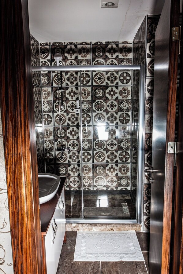 A bathroom with patterned tiles, a sink, and a shower.