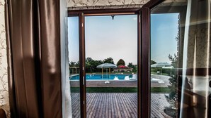 A view from a room with a wooden deck leading to a swimming pool, with a glass door and curtains. - My Green Otel (Kartepe)