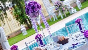 A poolside setting with white chairs and tables, purple floral centerpieces, and a clear view of the pool. - My Green Otel (Kartepe)