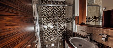 A modern bathroom with a glass shower enclosure, a white sink, and a wooden vanity.