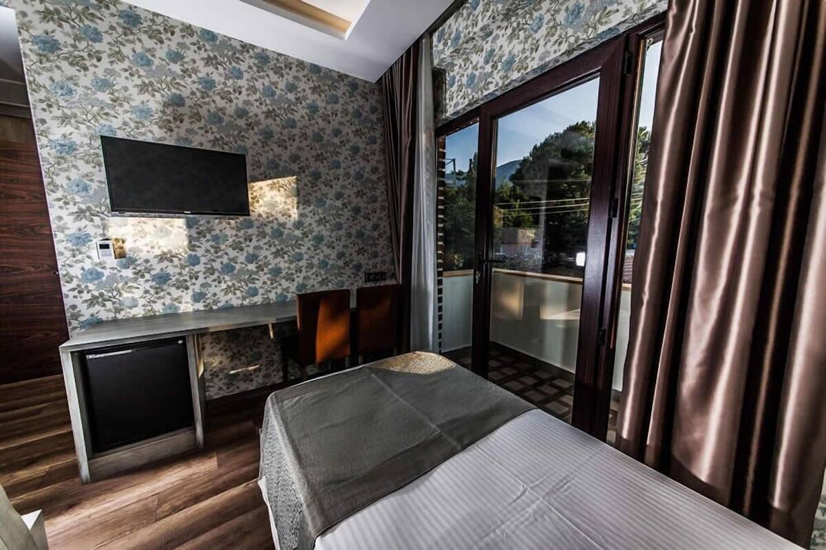 Een hotelkamer met een bed, een bureau, een televisie en een schuifdeur naar buiten.