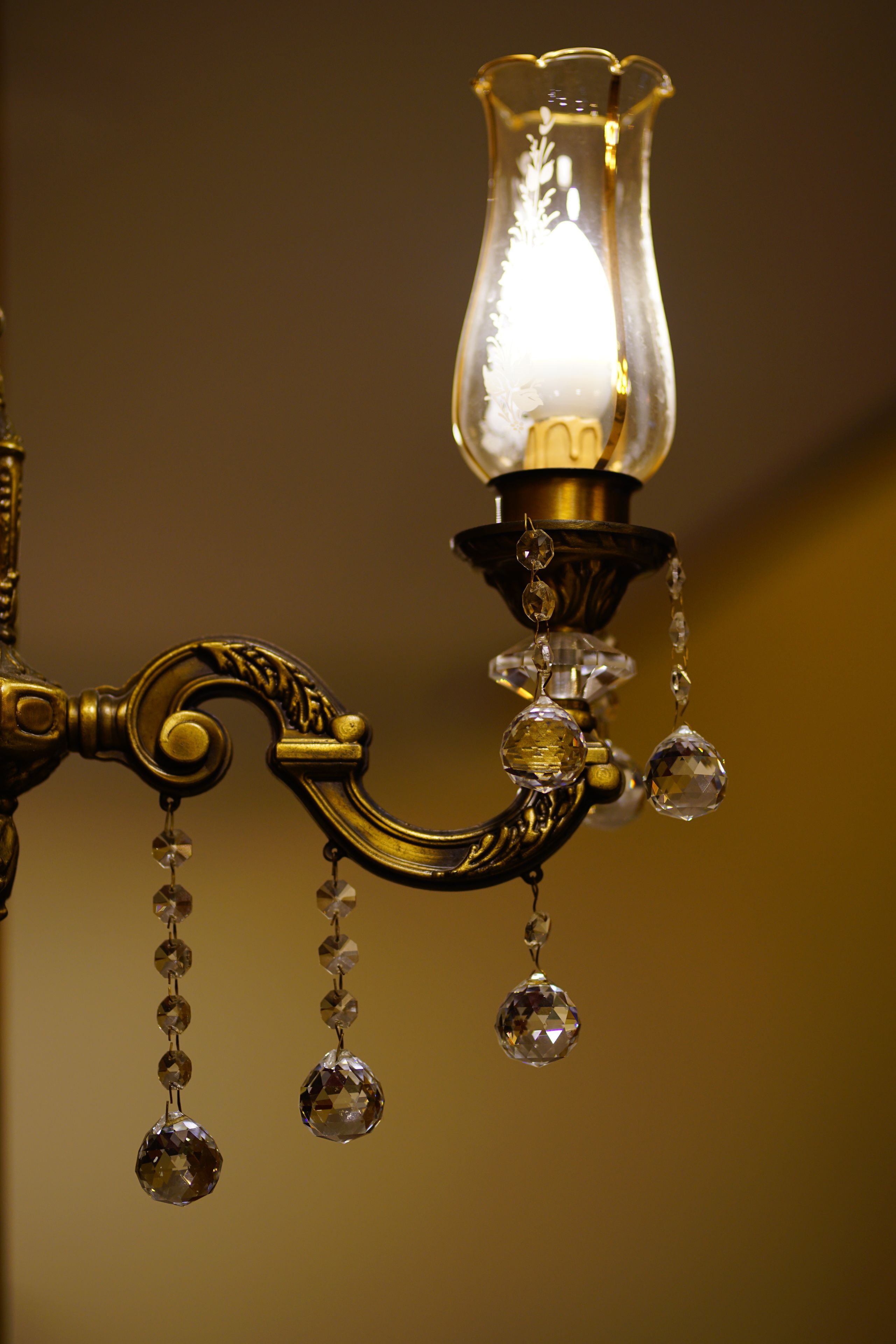 A chandelier with crystal decorations and a lit bulb.