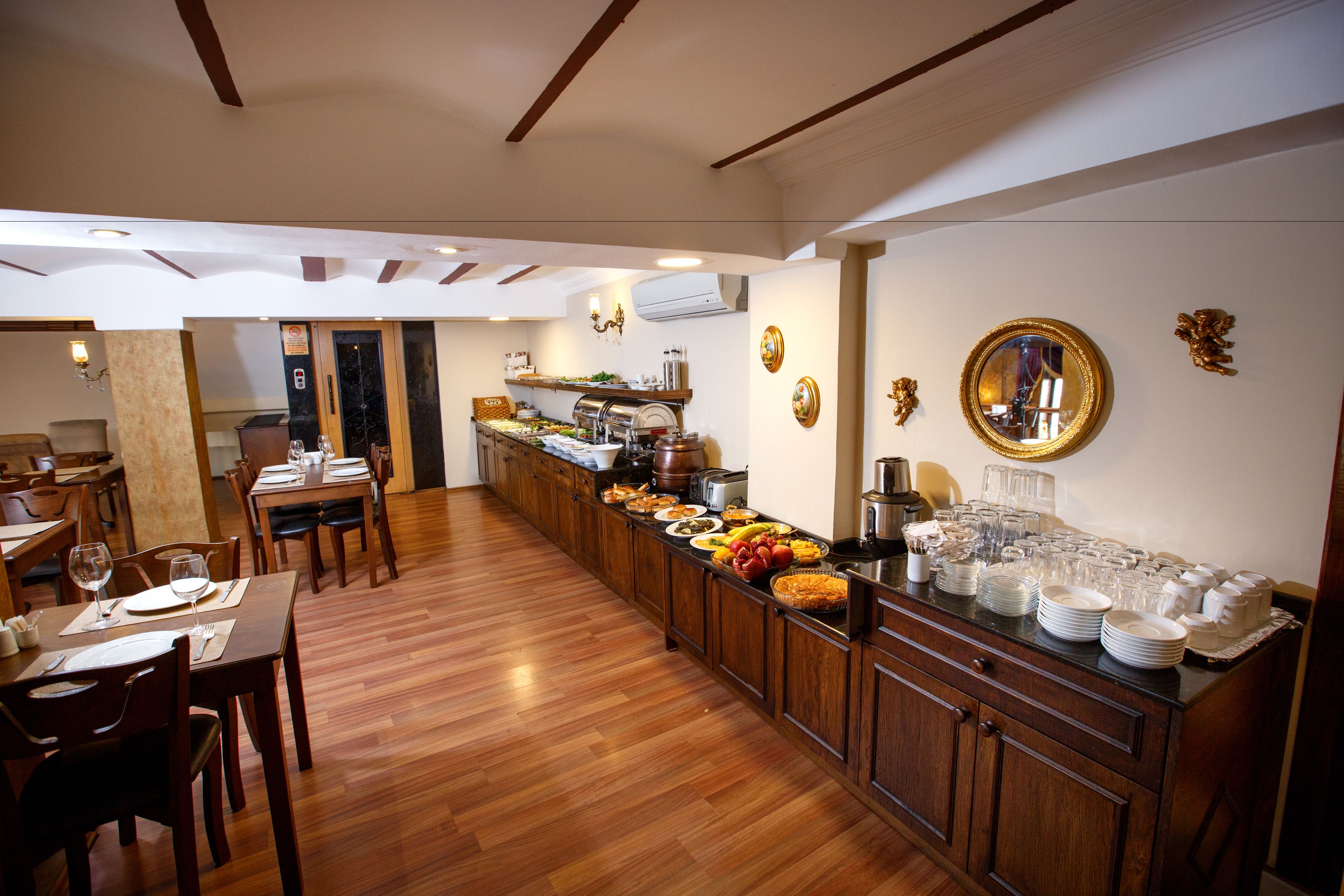 Un restaurante con suelo de madera, una barra de buffet y mesas de comedor con sillas.