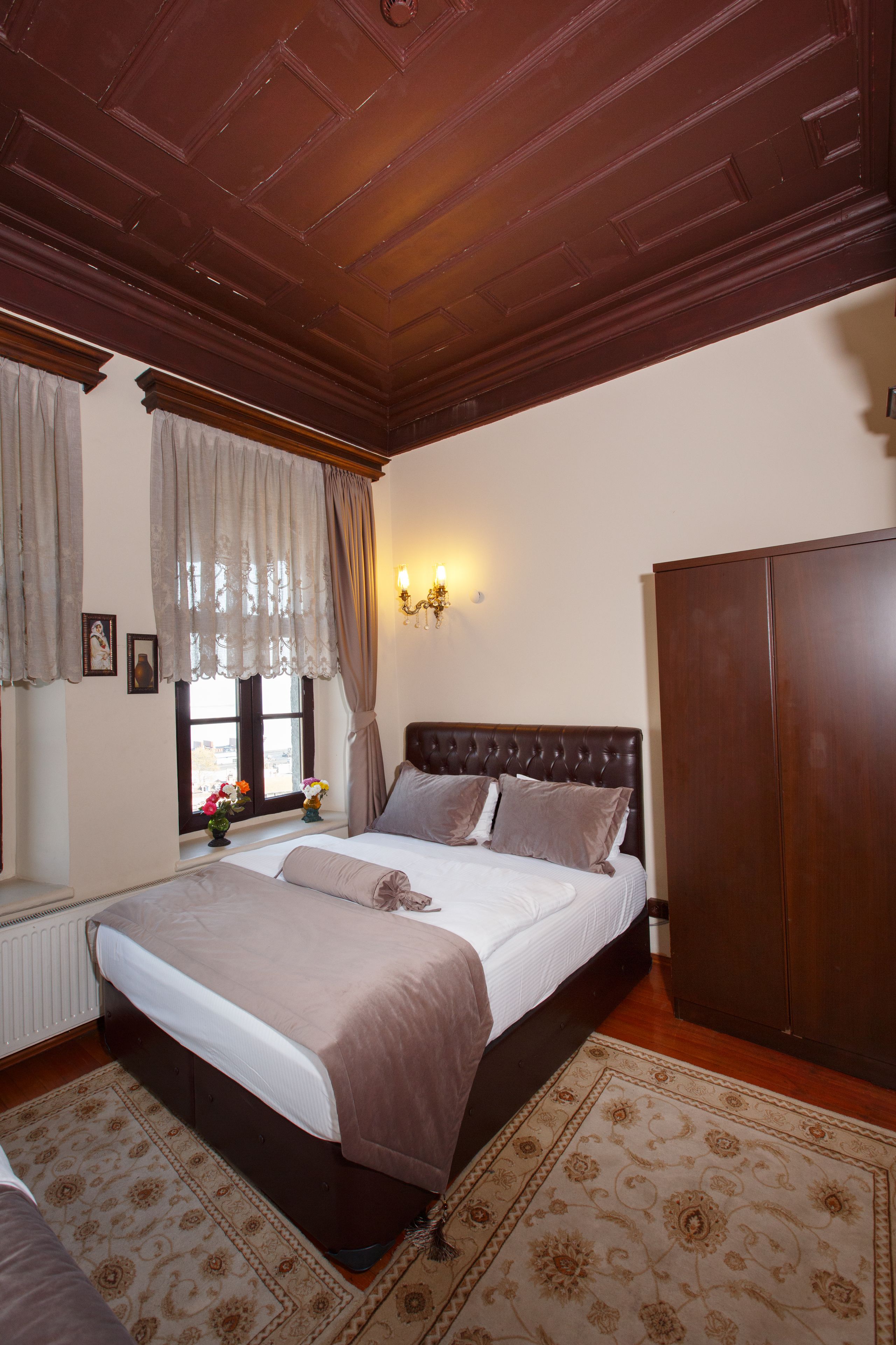 A bedroom with a large bed, wooden ceiling, and a wardrobe.