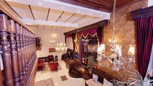 Un vestíbulo amplio con una imponente escalera, asientos cómodos y elegantes candelabros.