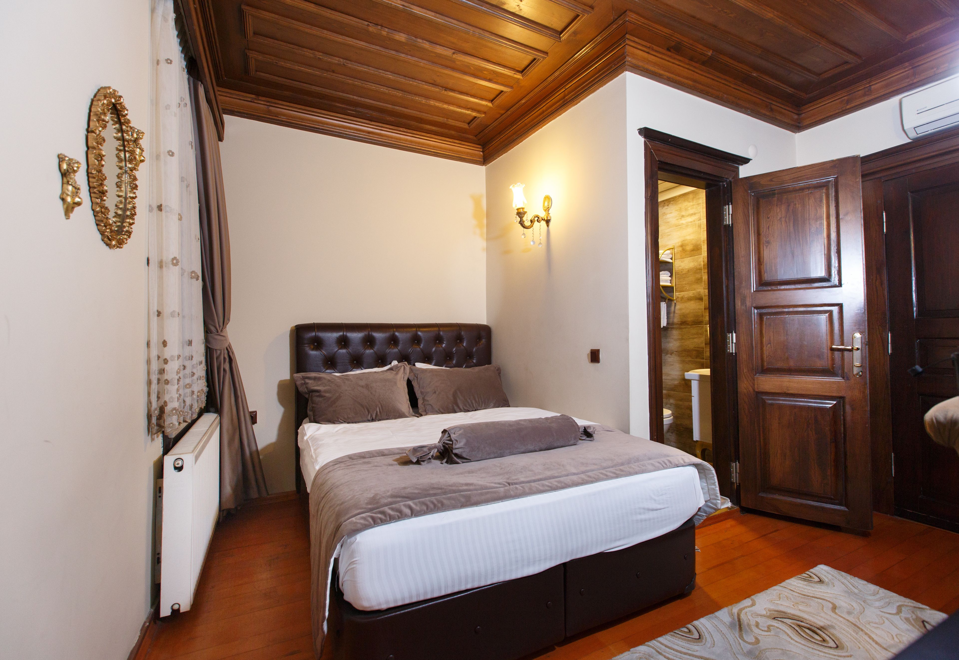 A bedroom with a large bed, wooden ceiling, and a wardrobe.