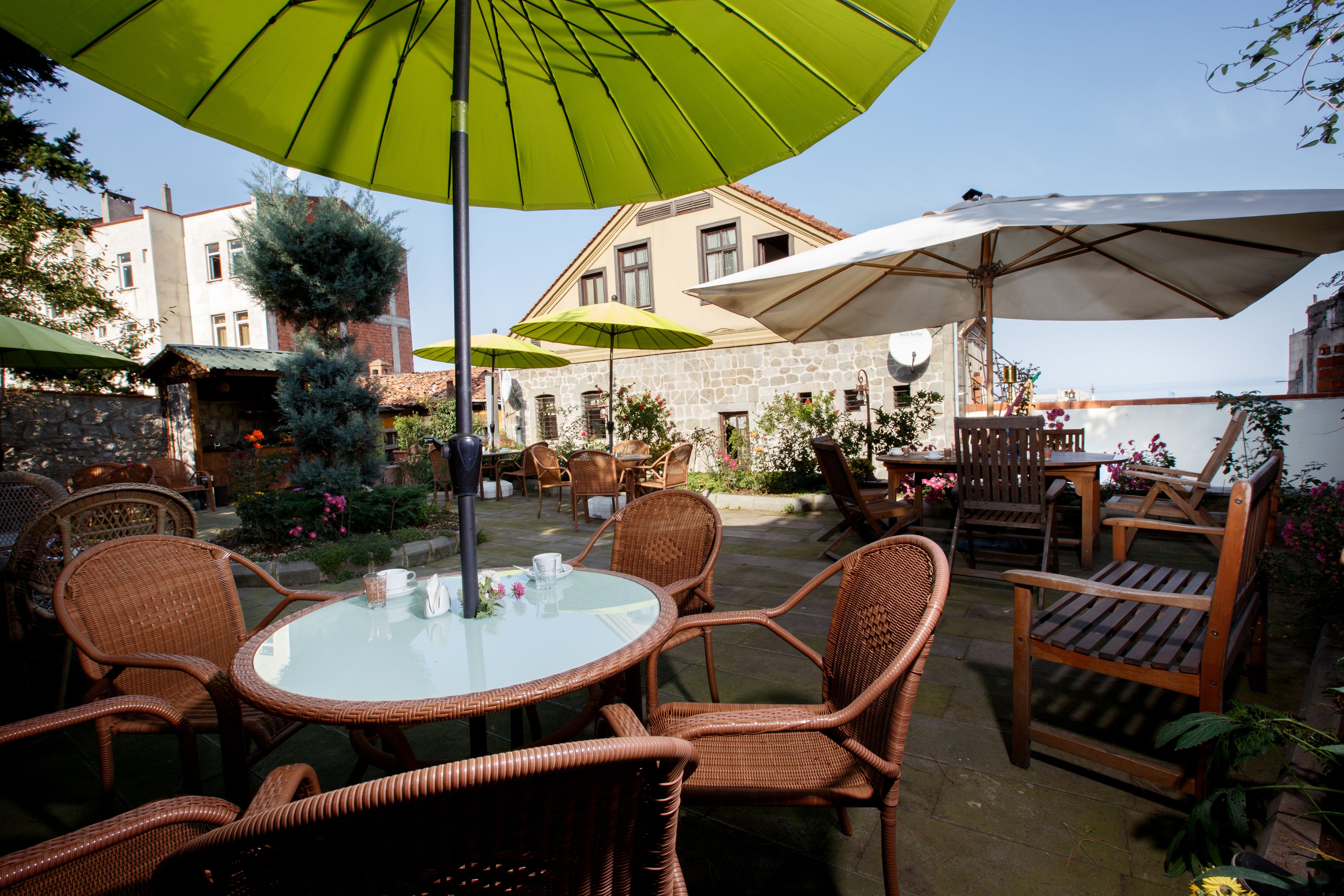 An outdoor patio with wicker furniture, a round table, and umbrellas providing shade.