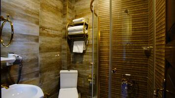 A bathroom with a glass-enclosed shower, a toilet, and a sink.