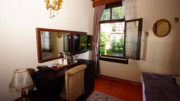 Una habitación con escritorio, silla, cama y ventana con cortinas.