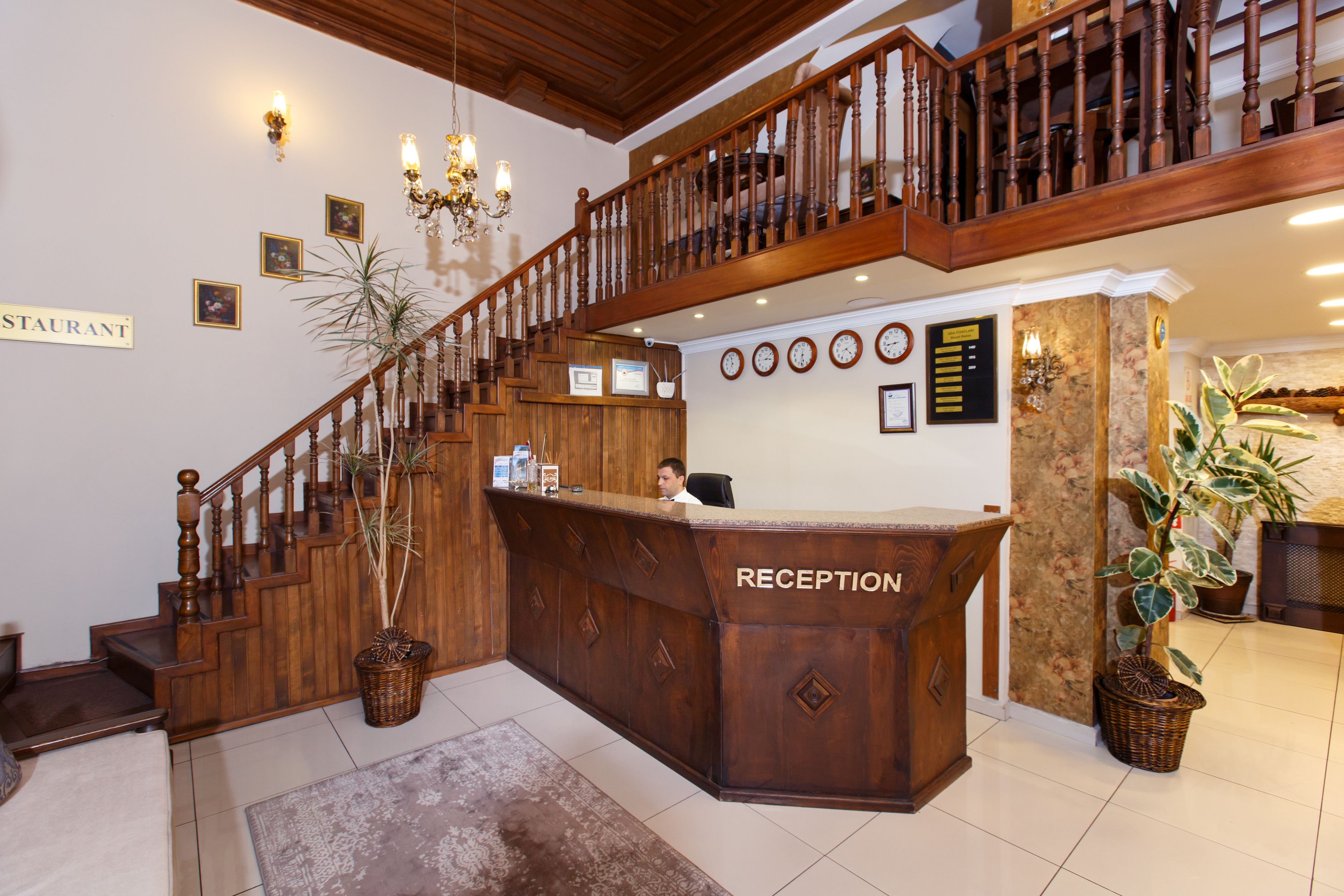 A reception desk with a sign, a staircase, and a wall with clocks.
