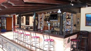 Un espace bar avec un comptoir, des tabourets et un écran de télévision.