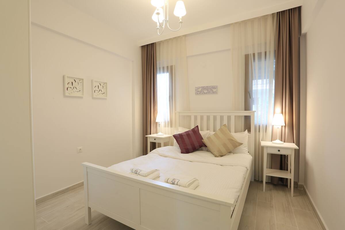 Une chambre à coucher bien rangée, avec un lit, des tables de chevet et une petite table de nuit.