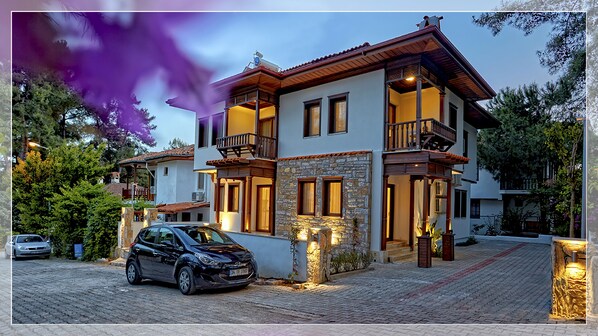 A two-story house with a stone facade, multiple balconies, and a car parked in front. - Alp Suites Lavanta (Ula)
