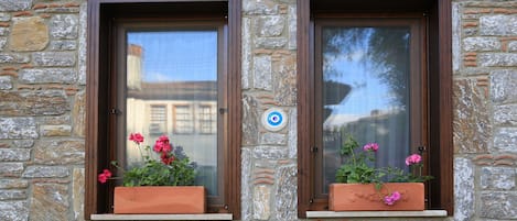Two windows with brown frames and flower boxes containing pink flowers.