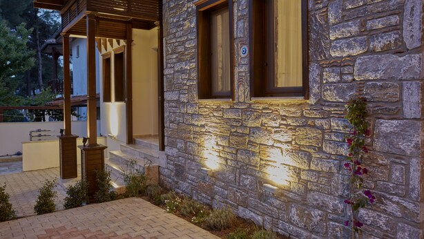 A stone building with a wooden porch and a well-lit exterior. - Alp Suites Lavanta (Ula)