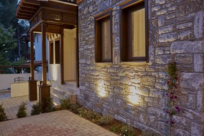 A stone building with a wooden porch and a well-lit exterior. - Alp Suites Lavanta (Ula)