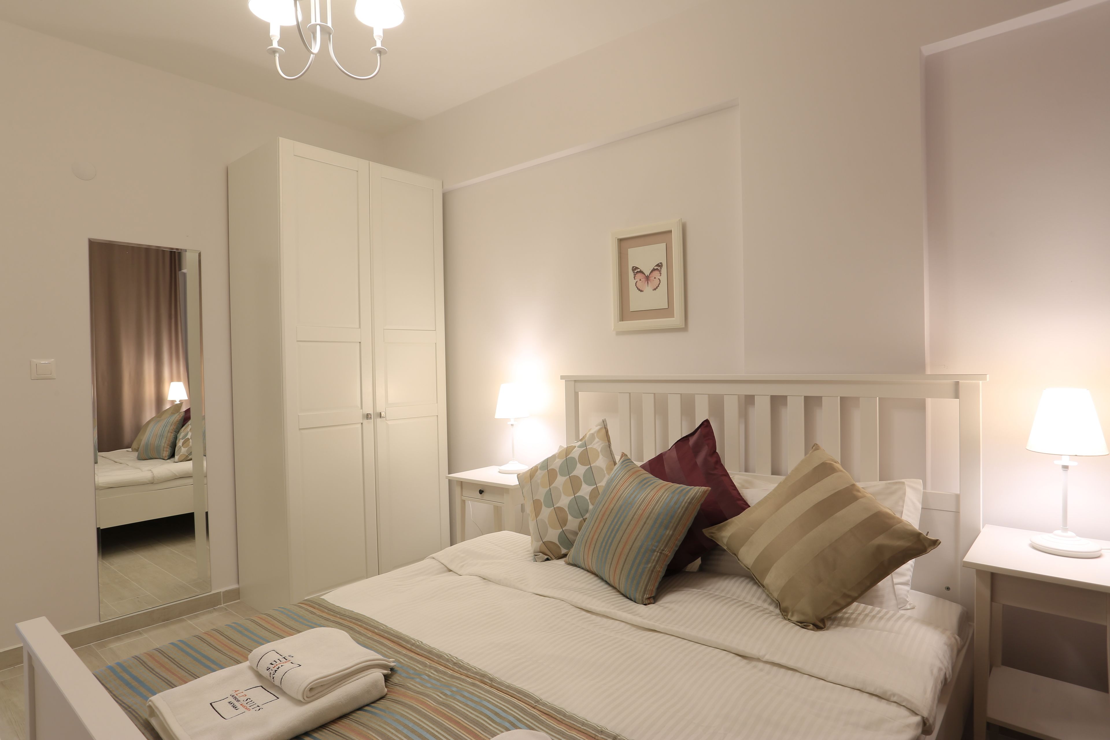 Un dormitorio ordenado con cama, mesitas de noche, un espejo y un armario.
