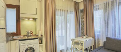 A compact living space with a washing machine, a dining table, and a sofa.