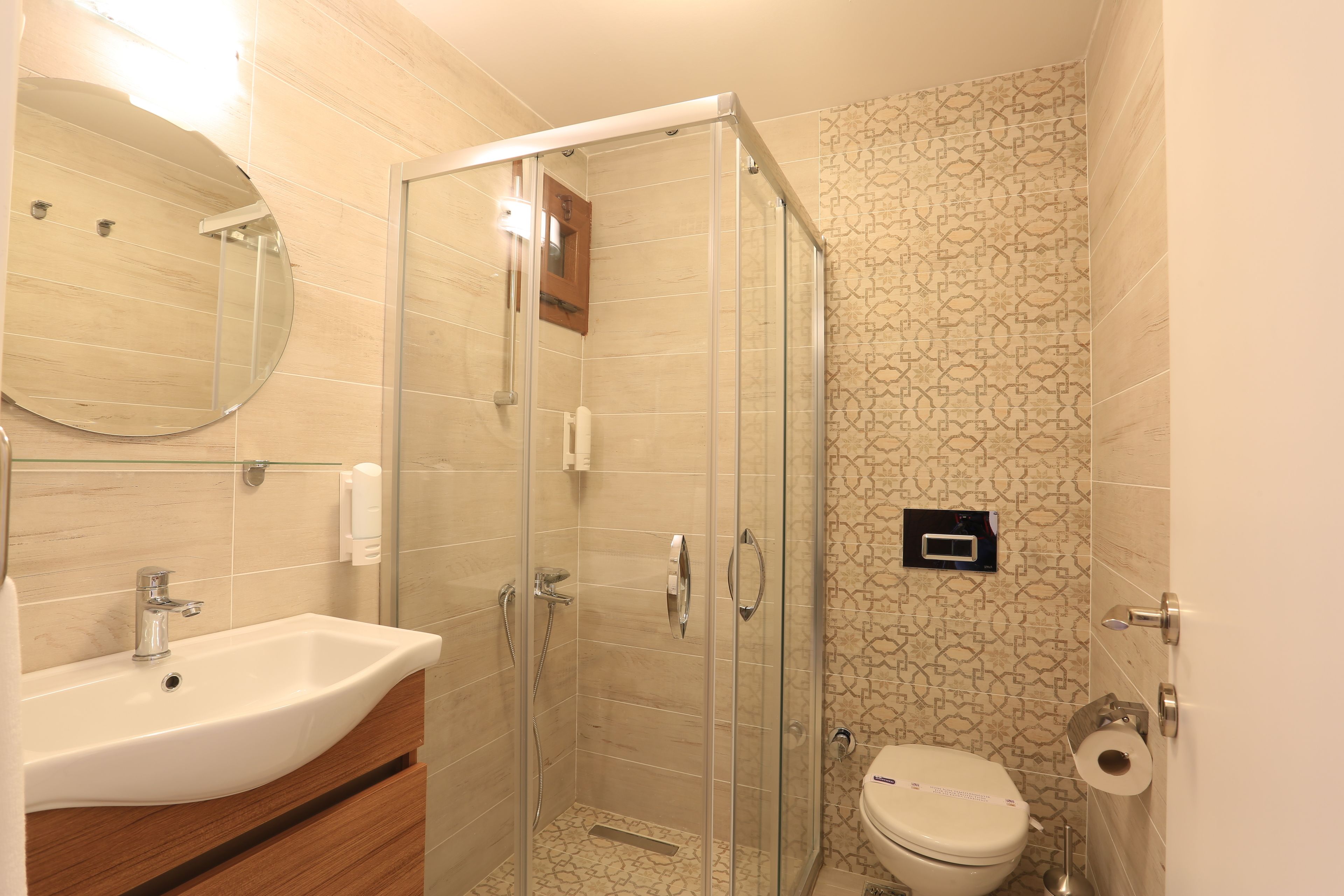 A bathroom with a glass-enclosed shower, a sink, and a toilet.