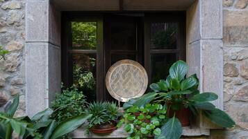 Un edificio de piedra con un vano de ventana, una placa decorativa de metal y varias macetas con plantas.