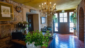 Un vestíbulo con pared de piedra, un candelabro, un mostrador de recepción y un cartel que dice "COMEDOR".