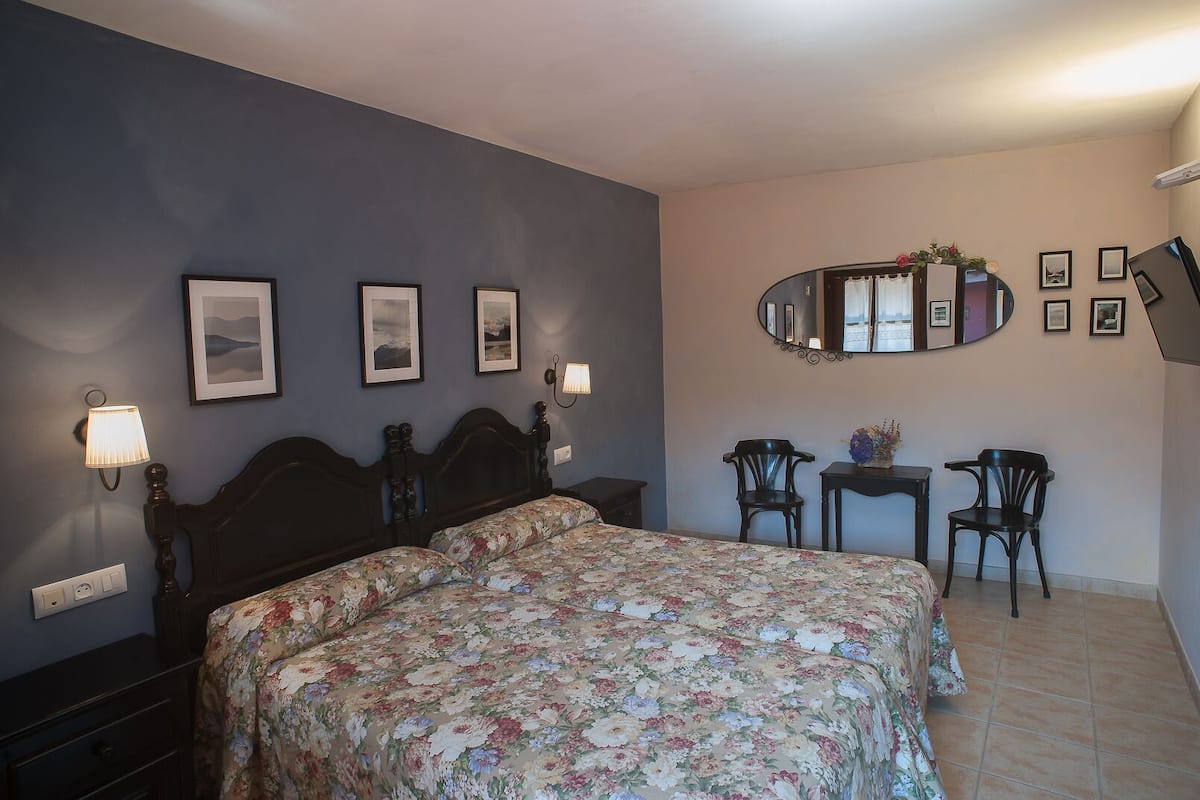 Un dormitorio con una cama, dos mesitas de noche, un espejo y dos sillas.