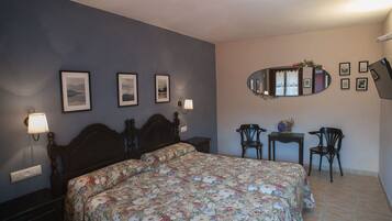 A bedroom with a bed, two bedside tables, a mirror, and two chairs.
