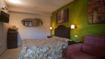 A bedroom with a bed, a nightstand, a dresser, a mirror, and two paintings on the wall.