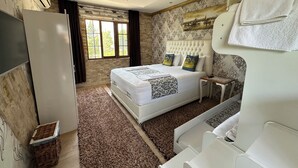 A bedroom with a large bed, a bedside table, a wardrobe, a window with curtains, and a wall with a decorative pattern. - Sinter Terasse House Hotel (Denizli)