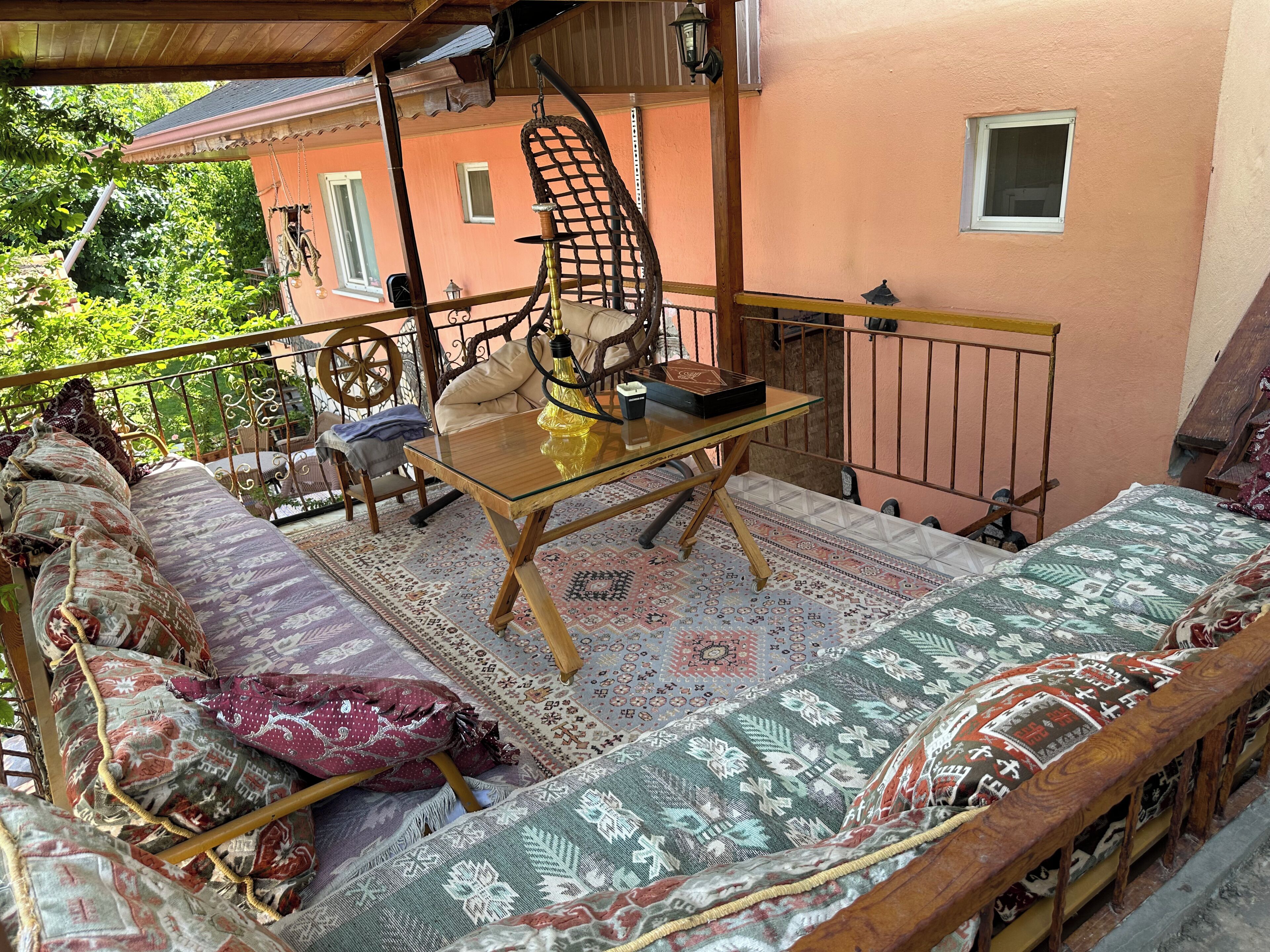 A balcony with a sofa, a table, and a hanging chair.