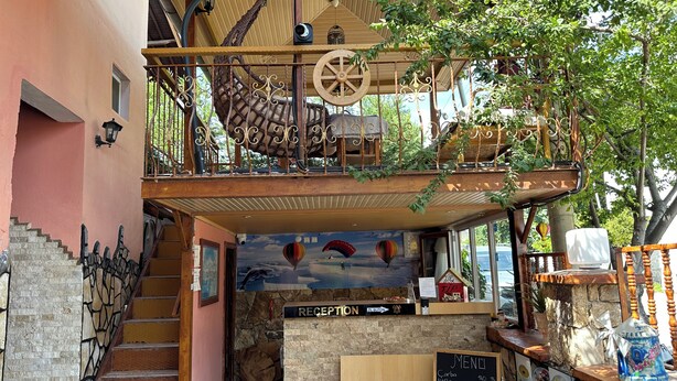 A rustic cafe with a wooden staircase, a reception desk, and a menu board. - Sinter Terasse House Hotel (Denizli)