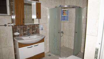 A bathroom with a sink, mirror, cabinet, shower, and toilet.