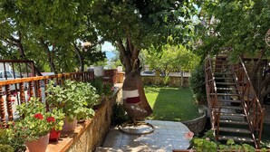 A garden area with a tiled pathway, potted plants, a wooden fence, and a staircase. - Sinter Terasse House Hotel (Denizli)