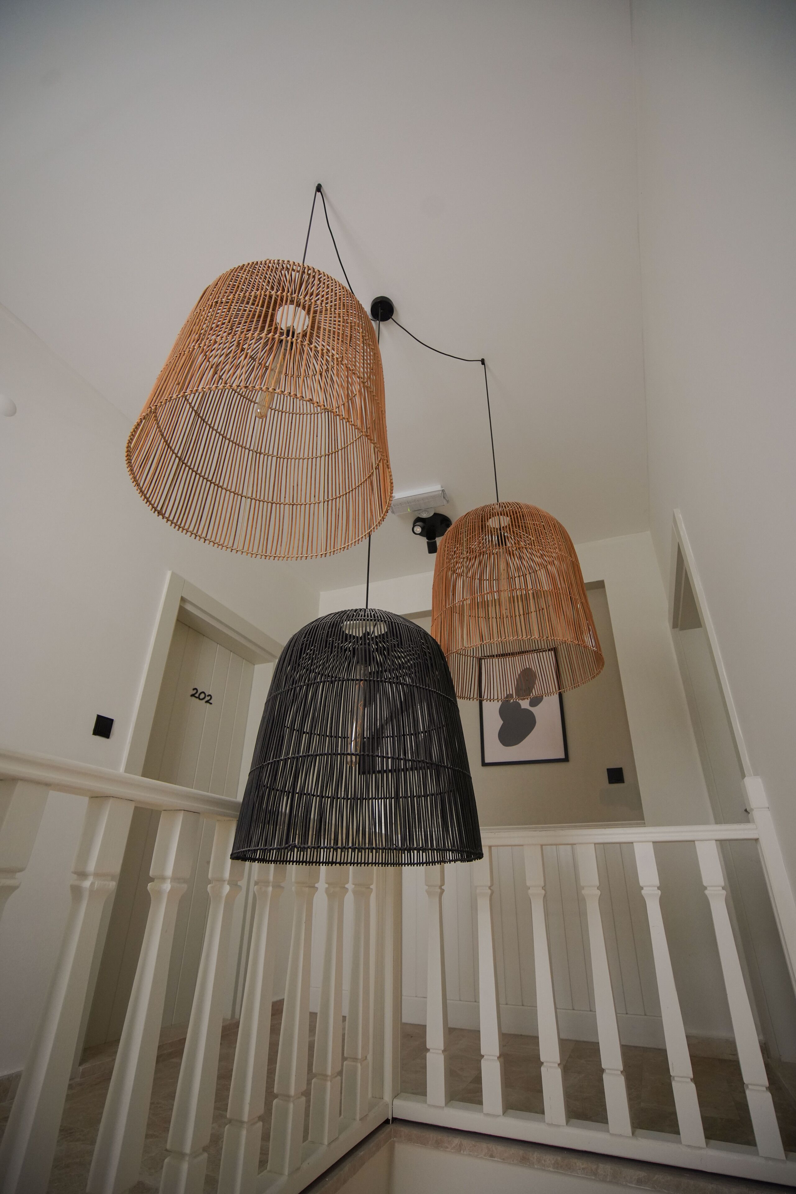 A staircase with white balustrades and two hanging wicker lamps.