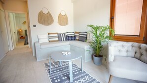 A modern living room with a sectional sofa, a round coffee table, and a potted plant. - Alp Suites Mandalin (Ula)