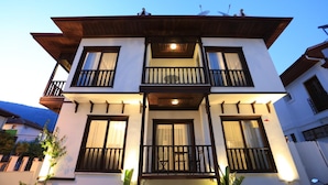 A two-story building with balconies, large windows, and a satellite dish. - Alp Suites Mandalin (Ula)