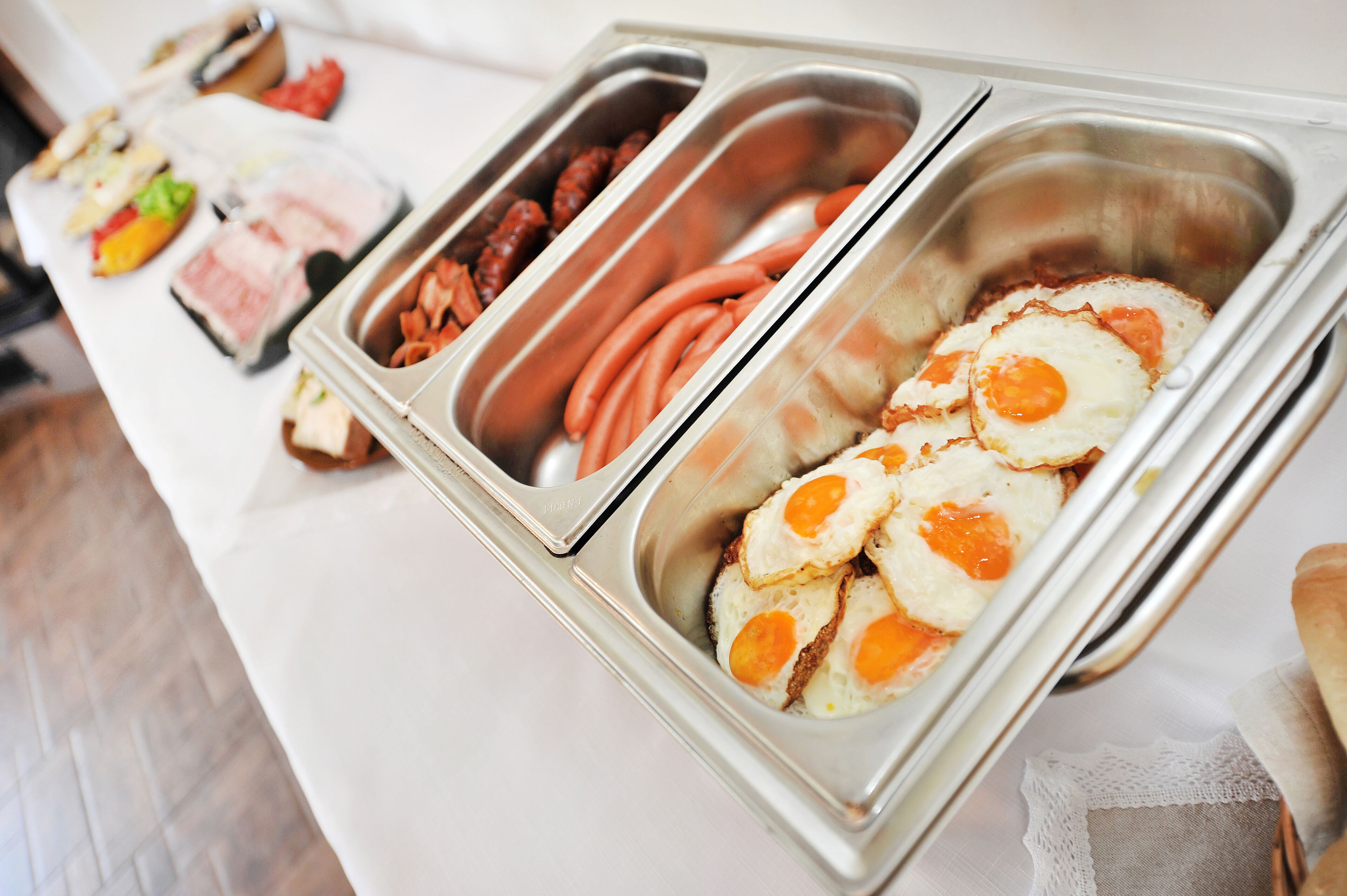 A buffet with various food options including sausages, eggs, and other meats.