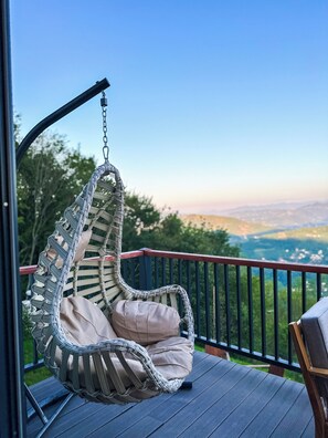 A wicker swing chair with cushions on a wooden deck with a view of a landscape. - Akcatepe Dag Evleri (Akçaabat)